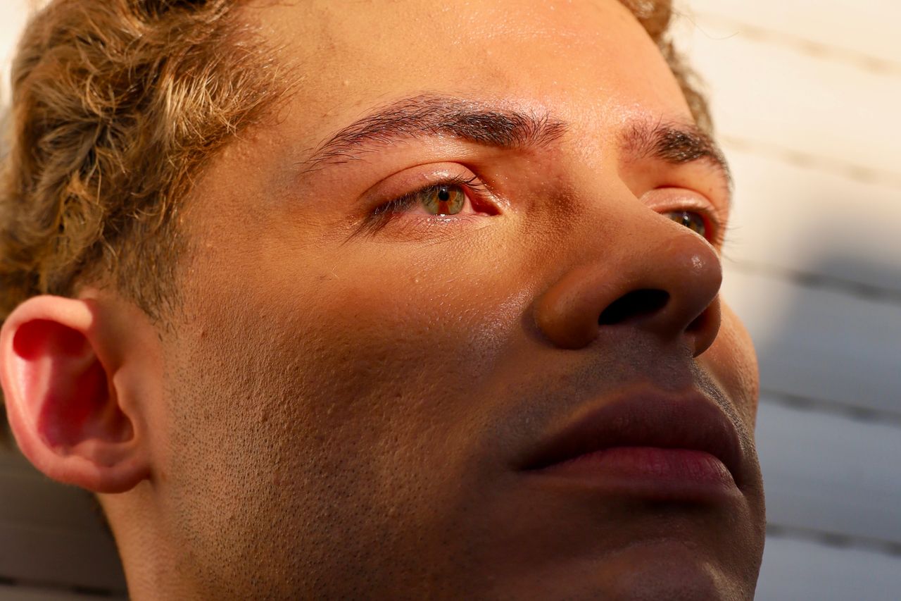 Close-up of a young man with sunlight casting shadows across his face.